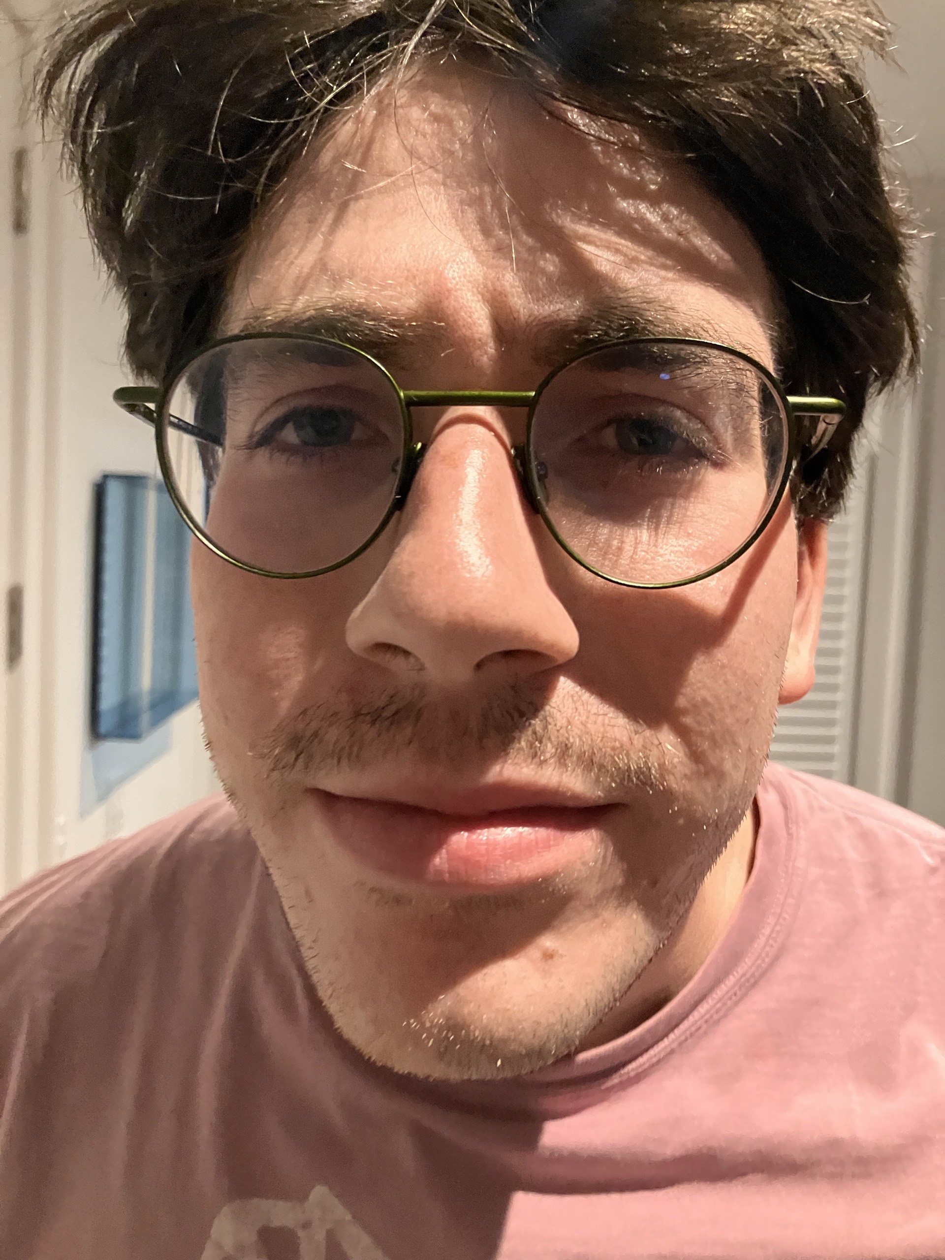 Close-up portrait with round glasses and a pink shirt